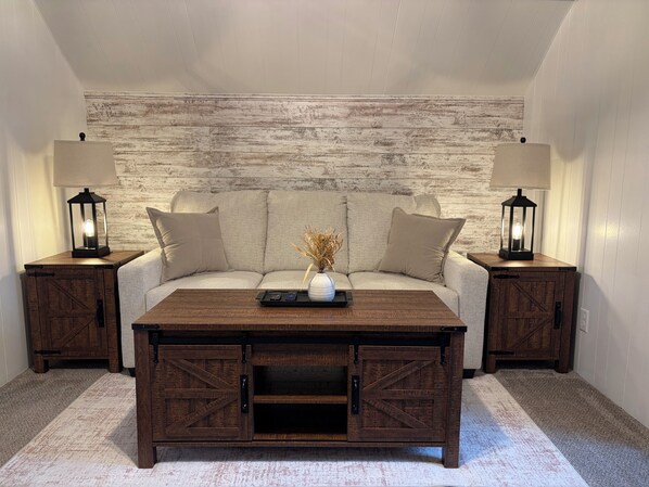 Une pièce comprenant un canapé, deux tables de chevet avec des lampes, une table basse et un mur au style rustique.