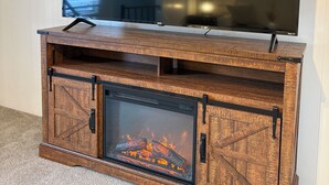 Un televisor de pantalla plana montado en un mueble de madera con chimenea debajo.
