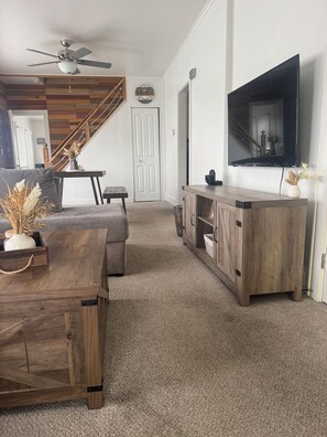 Ein Wohnzimmer mit einer Couch, einem Couchtisch, einem Fernseher und einem Holzkabinett.