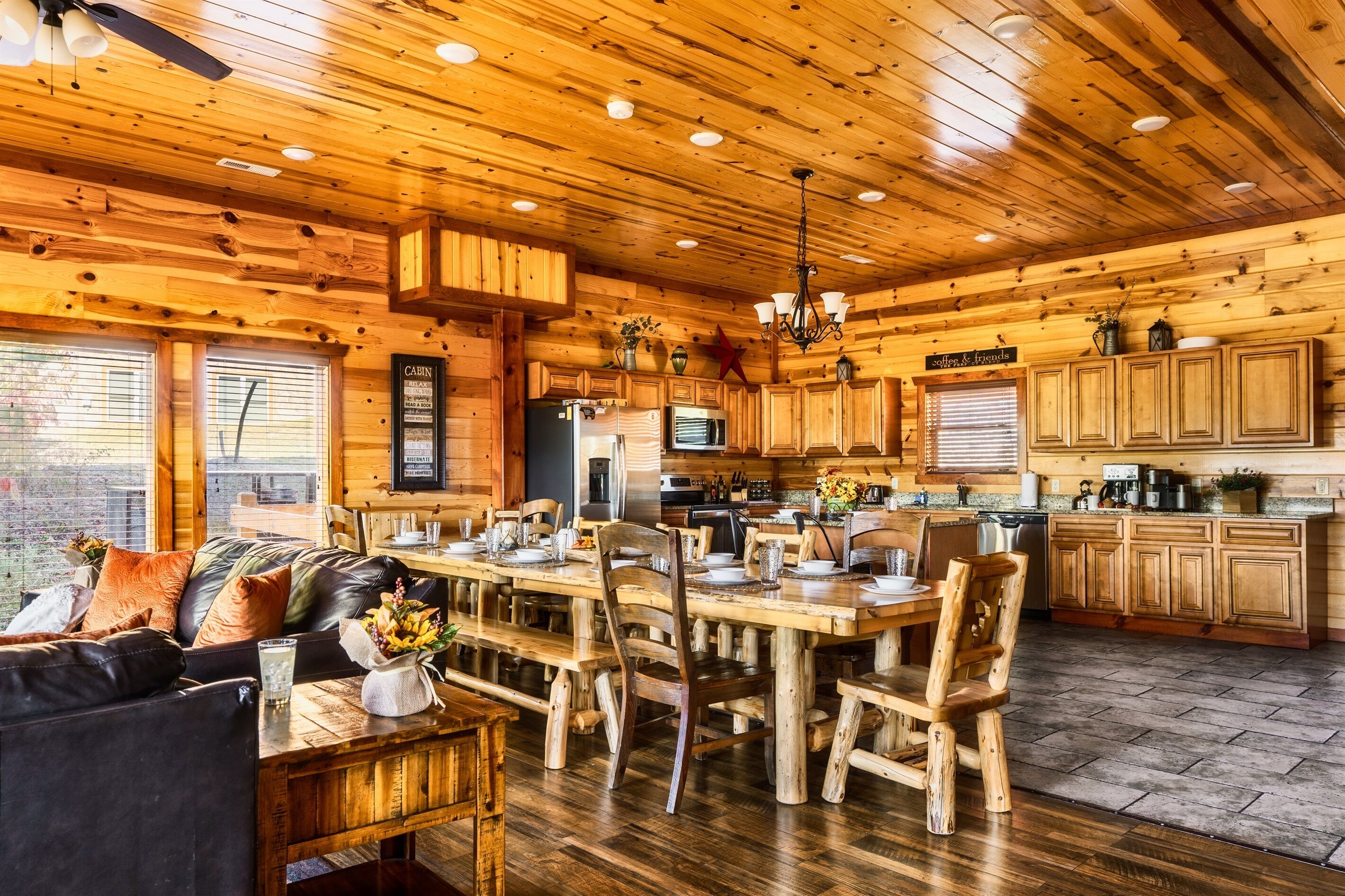 A spacious cabin interior with a wooden dining area, a sofa, and a kitchen with wooden cabinets and appliances.