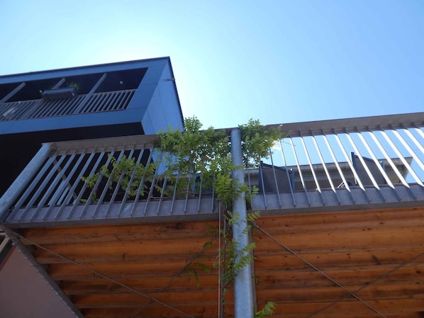 A modern building with a wooden deck and metal railing.