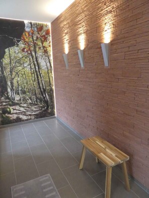 A room with a brick wall, a wooden bench, and a mural of a forest scene.