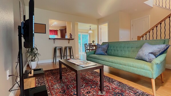 A living room with a green sofa, patterned rug, and a wooden coffee table.