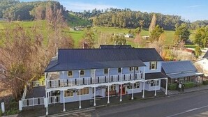 A two-story building with a balcony, a covered porch, and a view of a green landscape. - Wandering Trout (Mole Creek)