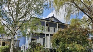 A two-story house with a balcony, surrounded by lush greenery and trees. - Wandering Trout (Mole Creek)