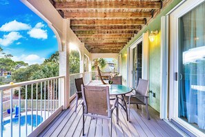 A covered outdoor area with a pool, wooden deck, and a table with chairs. - Top' Sea Turvy - Private Pool, 5 Minutes To Beach, Tennis & Pickleball Court! (St. George Island)