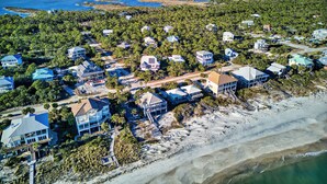 An aerial view of a coastal residential area with houses, a beach, and a clear view of the ocean. - Top' Sea Turvy - Private Pool, 5 Minutes To Beach, Tennis & Pickleball Court! (St. George Island)