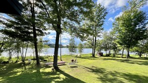 Zona verde con mesas de picnic y un cobertizo pequeño junto a un lago.