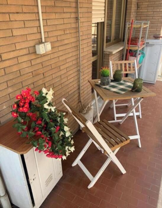 A patio area with a wooden bench, a small table, and a potted plant.