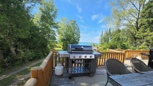 Un patio exterior con una parrilla, una mesa y sillas.