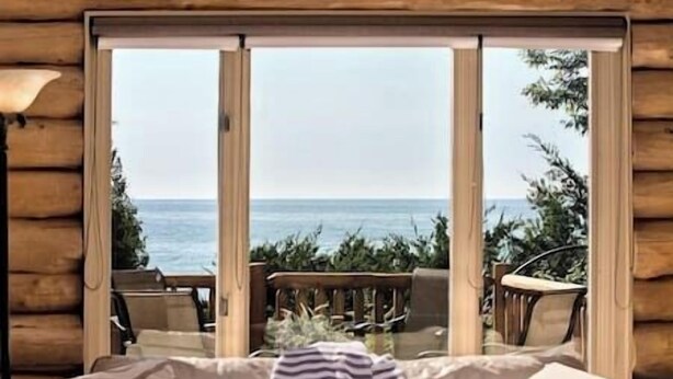 A log cabin room with a sliding glass door leading to a deck with outdoor furniture.