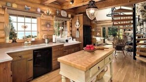 A spacious kitchen with wooden cabinetry, a central island, and a large window providing natural light.