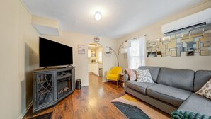 A living room with a grey sofa, a flat-screen TV, a yellow armchair, and a decorative wall. - Cozy Chalet Bungalow in West Park - Cleveland (Cleveland)