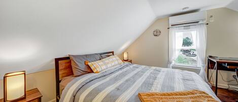 Ein Schlafzimmer mit Bett, Nachttischen, einer Lampe und einem Fenster mit Vorhängen.