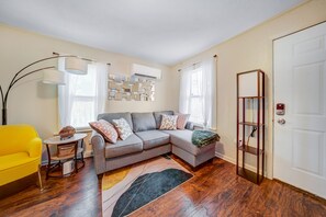 A living room with a sectional sofa, a yellow armchair, a floor lamp, and a bookshelf.
