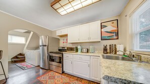 A modern kitchen with white cabinets, stainless steel appliances, and a granite countertop. - Cozy Chalet Bungalow in West Park - Cleveland (Cleveland)