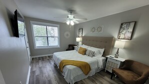 A bedroom with a bed, bedside tables, a chair, a ceiling fan, and artwork on the walls. - Chic, newly renovated townhome (North Charleston)