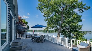 A deck with outdoor furniture, a flag, and a view of a lake.