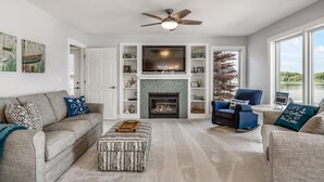 A living room with a fireplace, a ceiling fan, and a view of the outdoors.