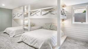 A bedroom with bunk beds, a window, and a small seating area.