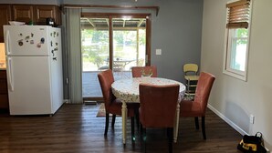 Un coin repas comprenant une table et des chaises, un ventilateur de plafond et un réfrigérateur.
