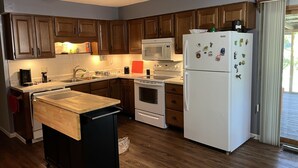 Une cuisine avec des meubles de rangement en bois, un four à micro-ondes, un réfrigérateur et un plan de travail en bois.