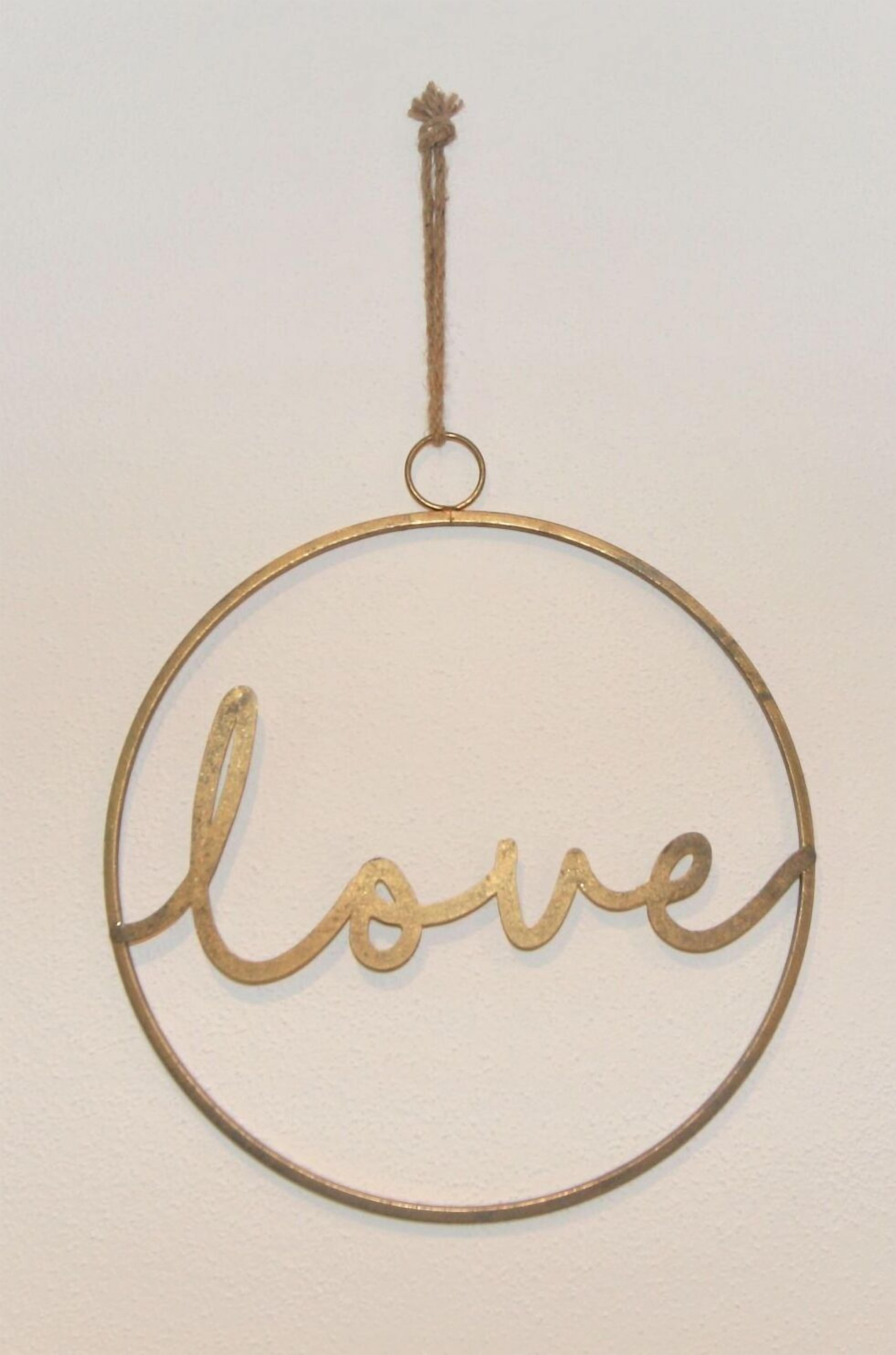 A circular metal ornament with the word "love" in cursive script, hanging from a loop.