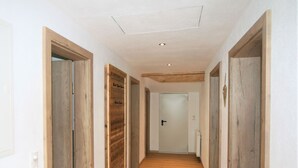En smal hall med trädörrar och ett vitt tak.