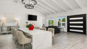 A modern kitchen with a marble island, a dining area with a white table, and a large chandelier. - NEW 5BR Villa w/ PrivatePool 3min to Eagle Beach (Noord)
