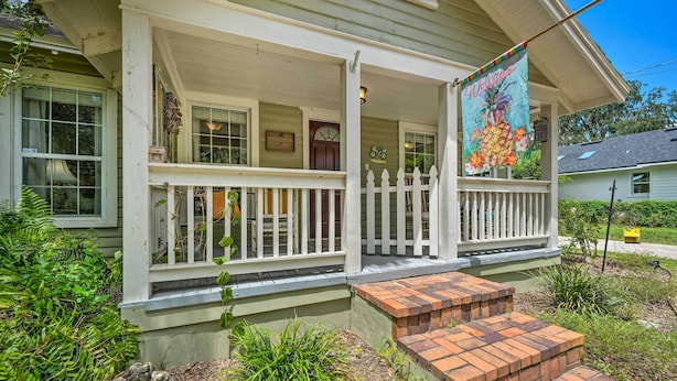 A house with a porch, a welcome banner, and a small garden area with steps leading up to the porch. - Walk to Mount Dora Historic District: Cozy Home! (Mt Dora)