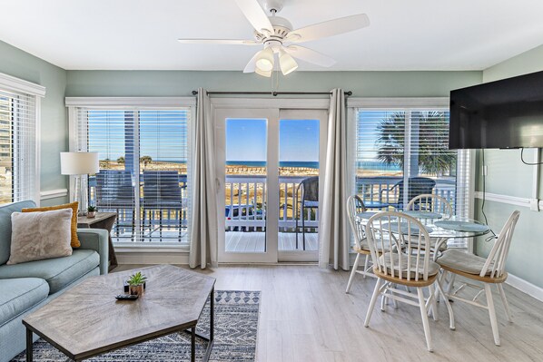 Relax in this beachfront living room with a sofa, coffee table, and dining area.