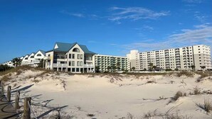 A beachfront hotel with multiple buildings, including a large hotel with a green roof and several smaller structures.