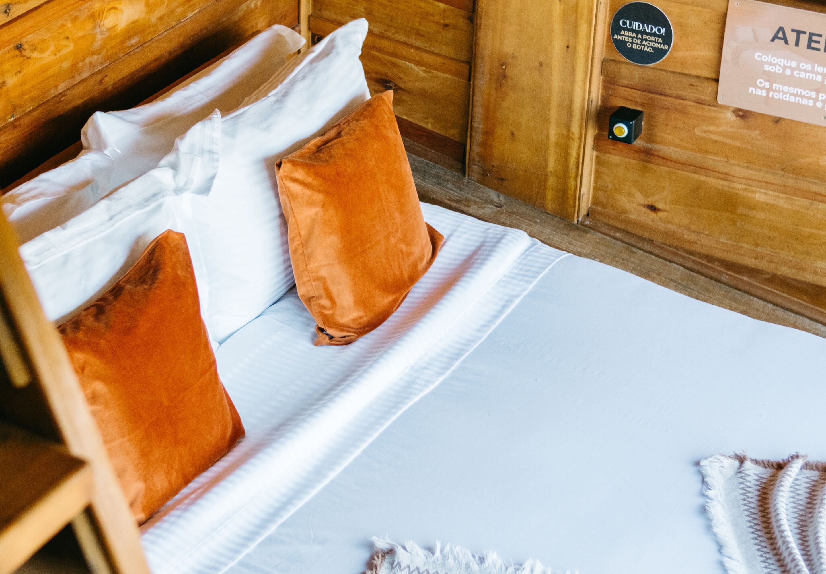 Una habitación tipo cabaña de madera con una cama, almohadas y un letrero en la pared.