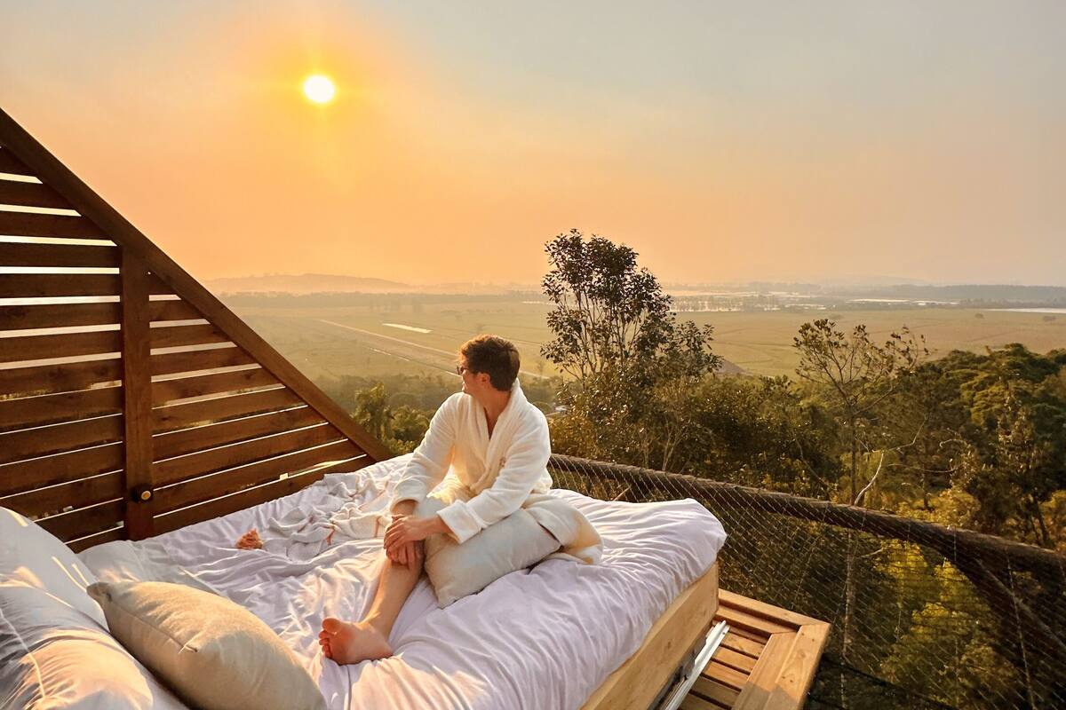 A person sitting on a bed with a view of a landscape.