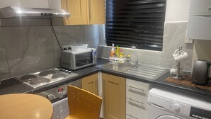 Ett kompakt kök med mikrovågsugn, spis, diskho och tvättmaskin.