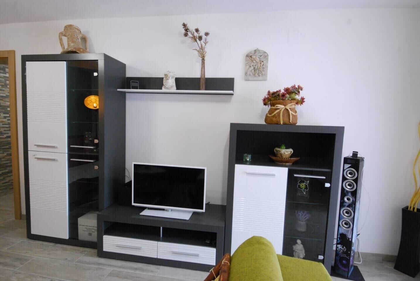 Una sala de estar moderna con un televisor de pantalla plana, un sistema de sonido integrado y objetos decorativos en estanterías.