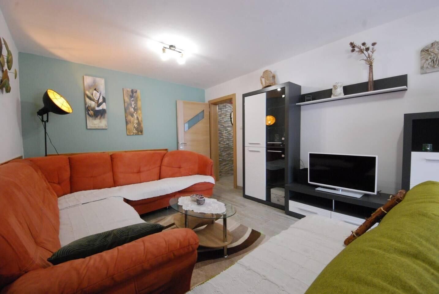 Olohuone, jossa on sohva, sohvapöytä, televisio ja kirjahylly.
