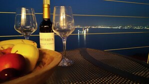 Une table avec une bouteille de vin, deux verres et un saladier de fruits.