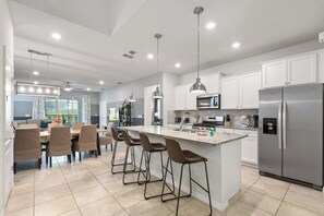 Una cocina moderna con una isla central, electrodomésticos de acero inoxidable e iluminación colgante.