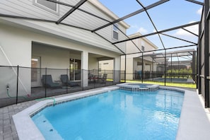 Ein Swimmingpool mit Whirlpool, umgeben von einer überdachten Terrasse mit Sitzgelegenheiten.