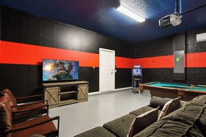 Ein Zimmer mit Billardtisch, Fernseher und einer Tür.