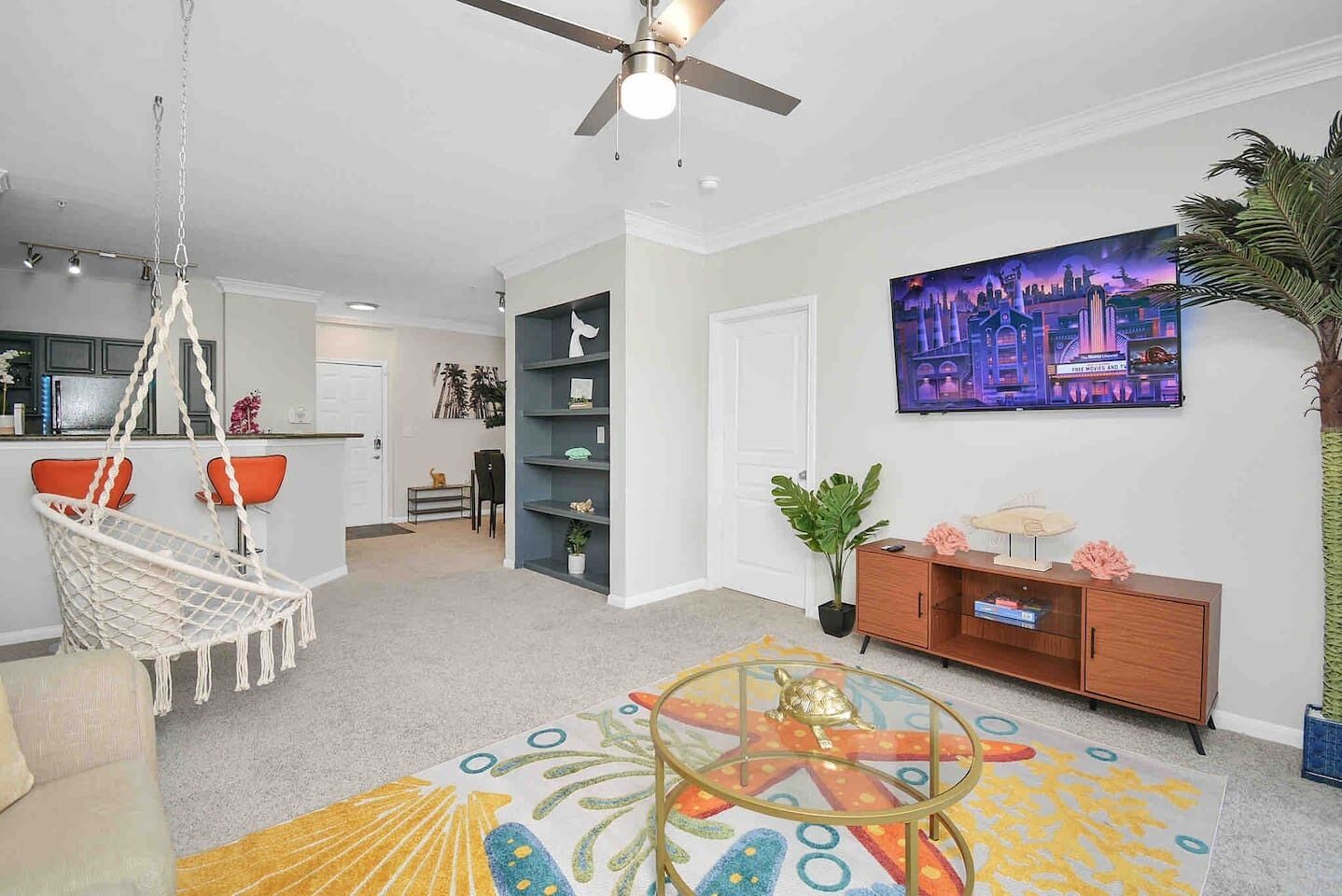 A modern living room with a hanging chair, a sofa, a TV, and a bookshelf.