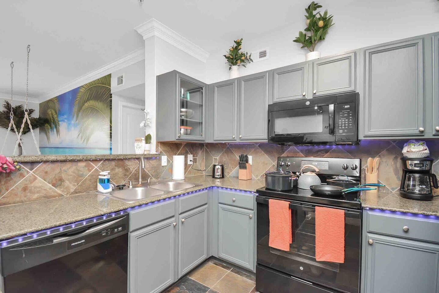A modern kitchen with grey cabinets, a microwave, a stove, and a coffee maker.