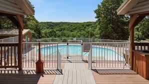 Une terrasse en bois avec une piscine, entourée d’une clôture blanche et d’un panneau indiquant les règles d’utilisation de la piscine.