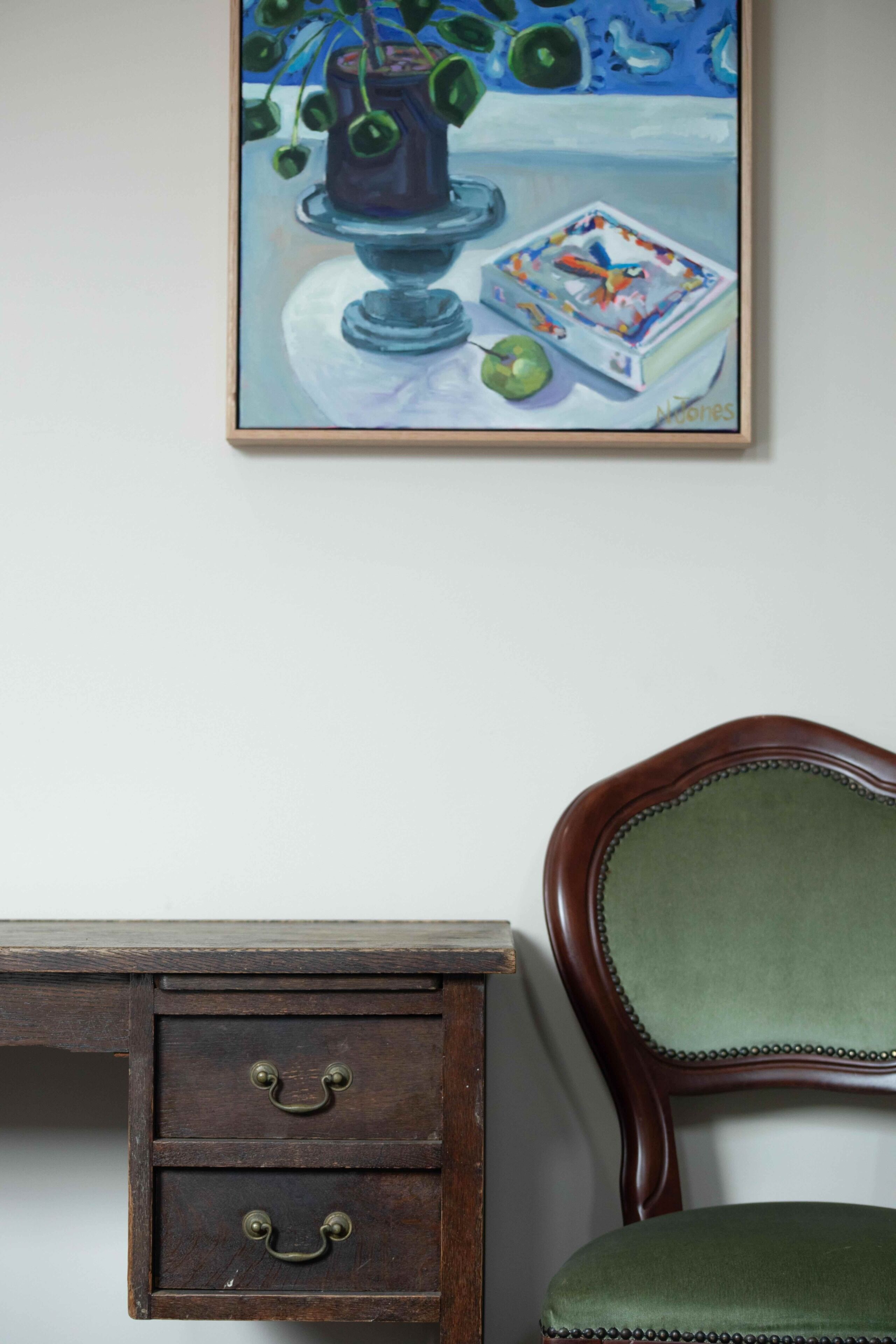 A wooden desk with drawers and a chair with a green cushion.