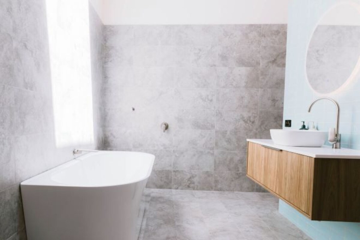 A modern bathroom with a freestanding bathtub, a wooden vanity, and a large mirror.