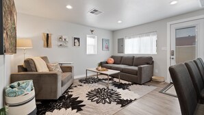 A modern living room with two sofas, a coffee table, and a patterned rug.