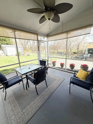 A sunroom with a ceiling fan, a glass table, and chairs.