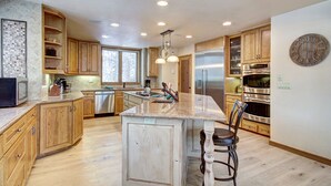 A spacious kitchen with wooden cabinets, stainless steel appliances, and a large island with bar stools.