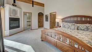 A bedroom with a wooden bed, a fireplace, and a hallway leading to another room.